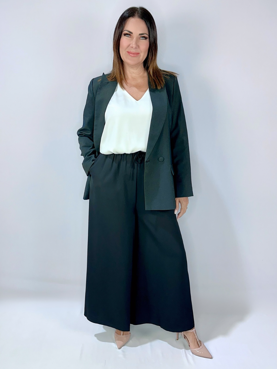 Woman wearing Kerry's Style Sessions black blazer with wide-leg black pants and a white V-neck top, styled with nude heels.