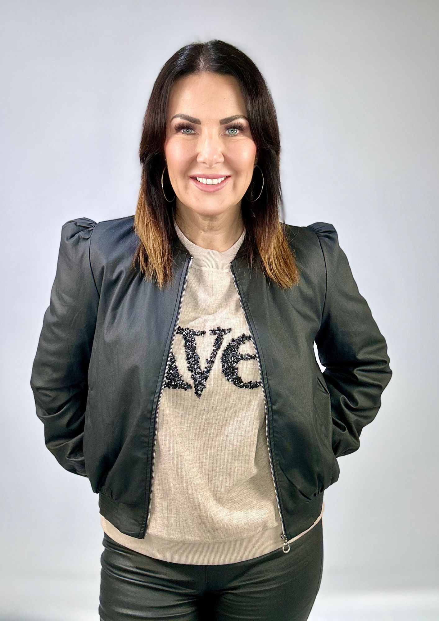 Kerry's Style Sessions black bomber jacket over a beige sweater with embellished text.