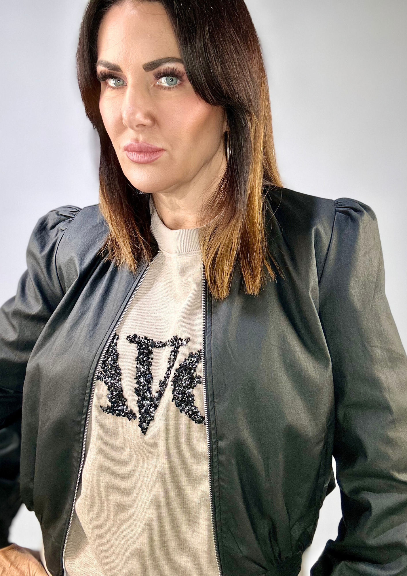 Woman wearing Kerry's Style Sessions black bomber jacket over a beige embellished sweater.